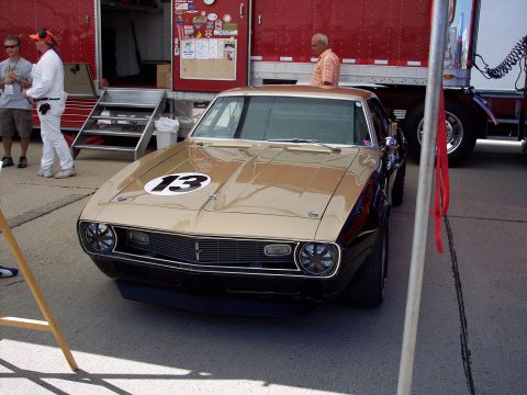 1971 Ford Mustang - A gold and black 1969 Camaro with a prominent racing number 13 on its hood is parked outdoors.