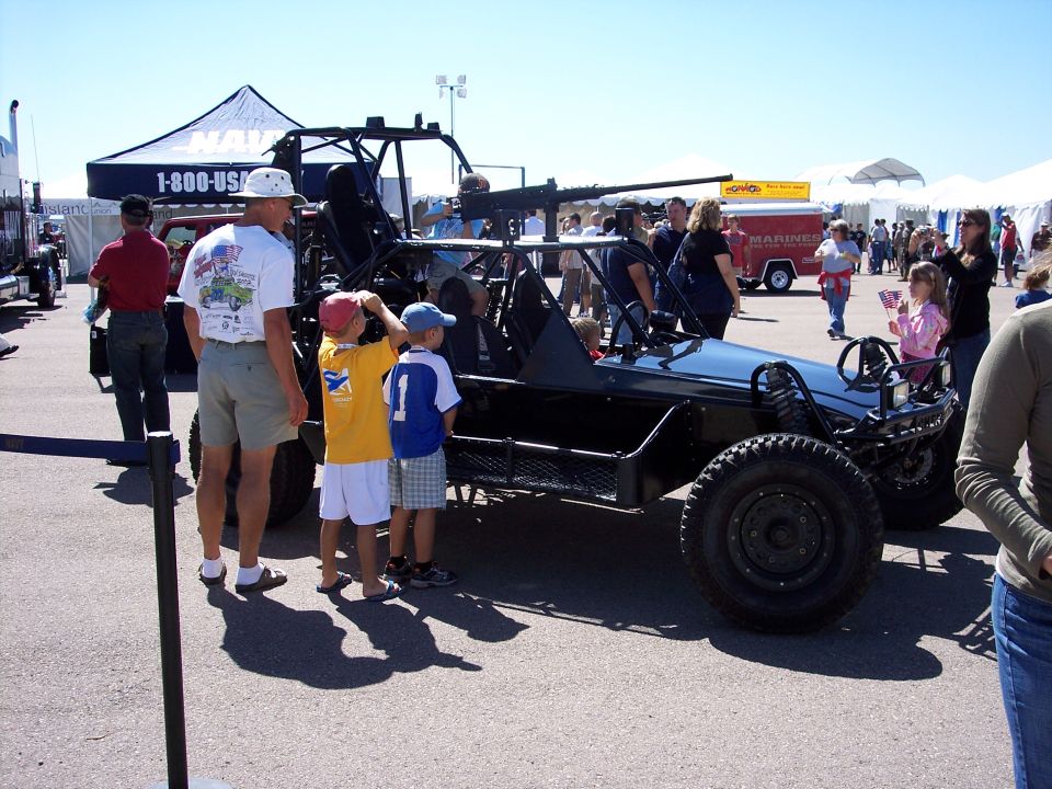 Military buggy with a machine gun mounted on top, people looking at it