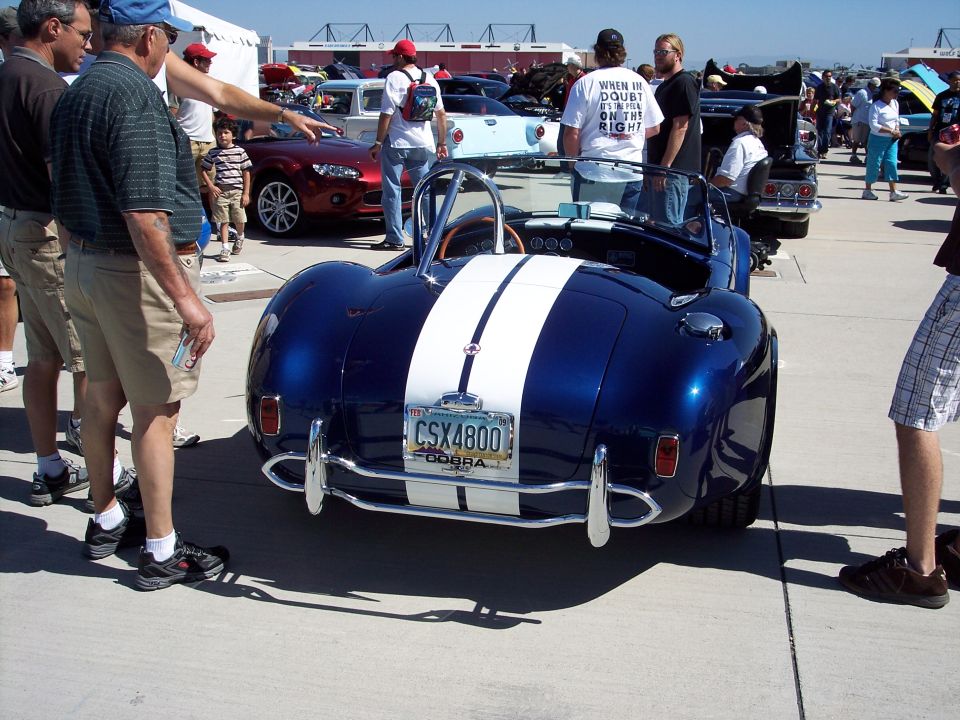 Blue convertible with dual white racing stripes and chrome bumpers. License plate reads CSX4800 COBRA