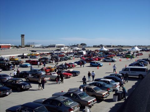 1971 Ford Mustang - A large gathering of cars and people are present at an outdoor event on a sunny day.