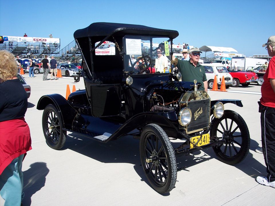 Black Ford Model T touring car with a black soft top, viewed from the front-right