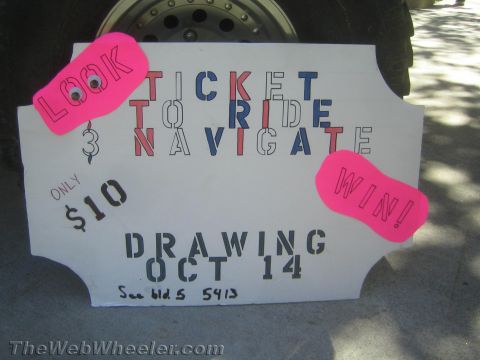 1990 Ford Bronco - hand-lettered white raffle sign with pink tags reading Look, Ticket To Ride Navigate Win, only $10, drawing Oct 14, leaning on a tire.