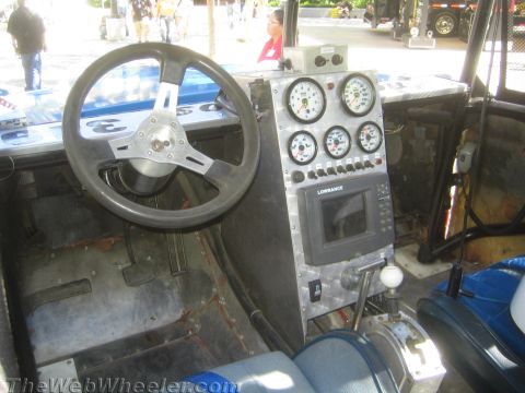 1990 Ford Bronco - Bare metal race-truck cockpit featuring a black steering wheel, a stacked gauge cluster and a Lowrance display on an aluminum panel.