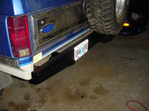 1985 Ford Bronco - The rear of a blue Ford Bronco is shown, a new bumper and a spare tire mounted on the tailgate.