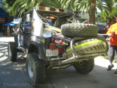 1990 Ford Bronco - Rear view of a lifted Jeep showing a tubular bumper, spare tire, winch and a California license plate reading 5LFY211 near palm trees.