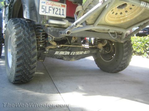 1990 Ford Bronco - Low view under a lifted Jeep revealing the rear axle, links and a skid plate lettered Rubicon Extreme-Out, with plate 5LFY211 above.
