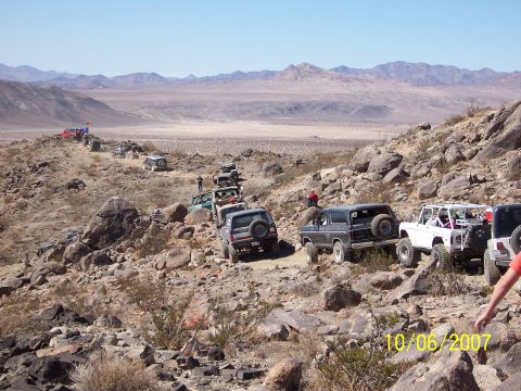 1996 Ford Bronco - A convoy of off-road vehicles navigates a desert landscape under a clear blue sky.