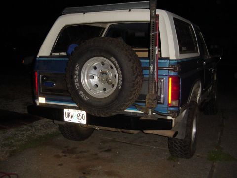 1985 Ford Bronco - The rear of a blue Ford Bronco is shown, a spare tire and a visible license plate.