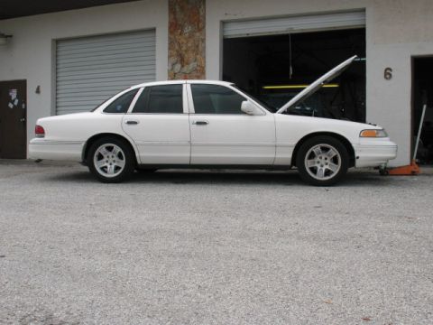 1997 Ford Crown Victoria - White 1997 Ford Crown Victoria parked with its hood up in front of a garage.