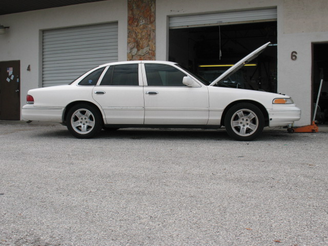 1997 Ford Crown Victoria parked outside a garage with hood open