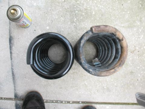1997 Ford Crown Victoria - A new black coil spring is compared to an old, rusted one, with a can of spray paint nearby.