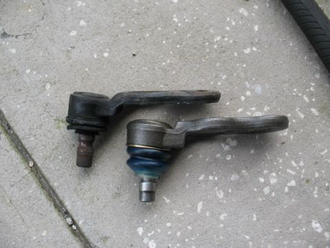 1997 Ford Crown Victoria - Two ball joints are shown on a concrete surface. One ball joint has a blue protective boot.