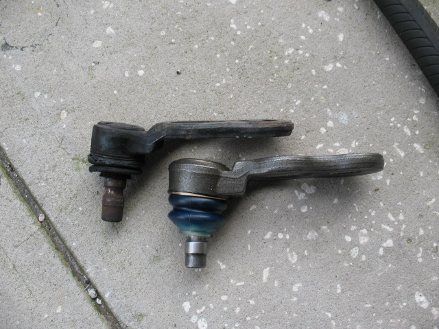 Two ball joints on concrete, one with blue boot