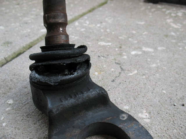 Worn ball joint with torn rubber boot and grease leakage