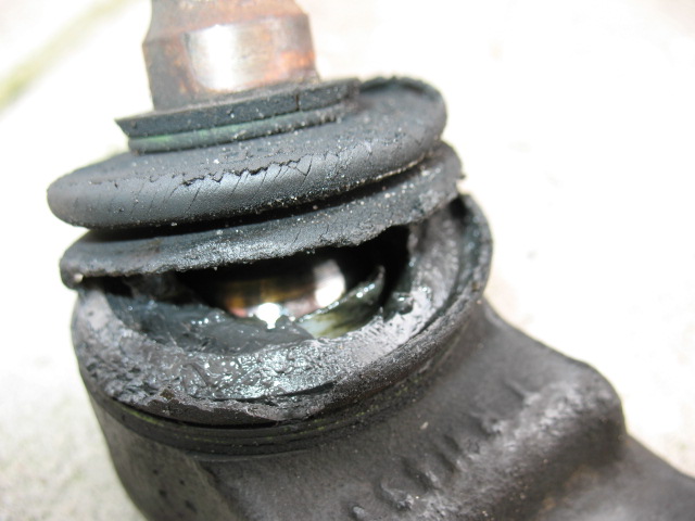 torn rubber boot on a ball joint with grease leaking out