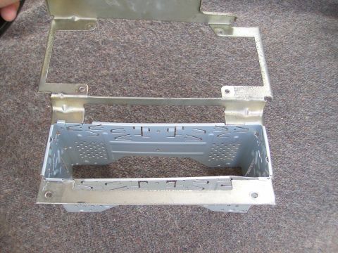 1979 Ford F-100 - This metal radio mounting bracket is shown from a top-down perspective, resting on a carpeted surface.