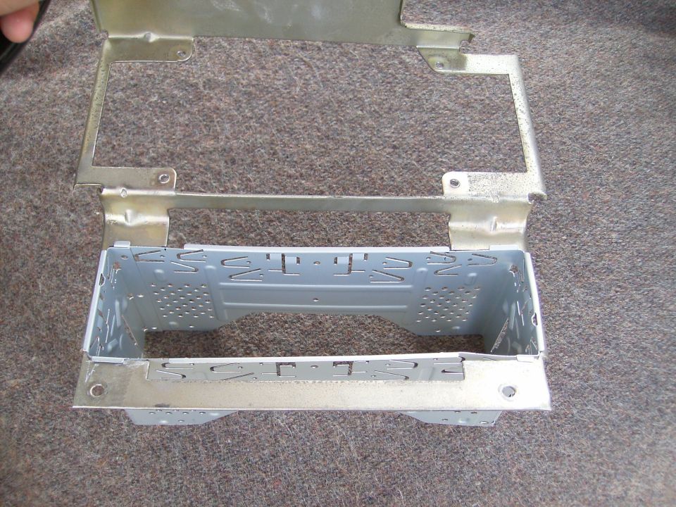 Metal radio mounting bracket with perforations and tabs, resting on carpet