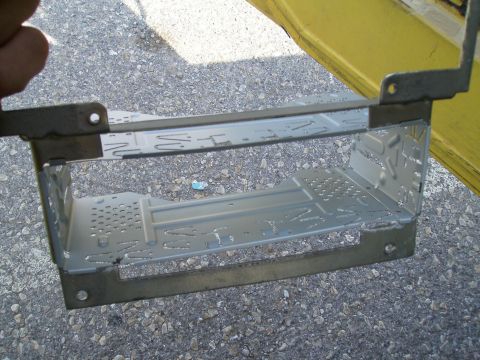 1979 Ford F-100 - Metal mounting bracket for a car radio, shown outdoors on a gravel surface.