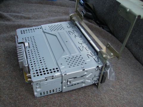 1979 Ford F-100 - Car stereo unit and its mounting bracket are shown close-up, resting on a fabric surface.