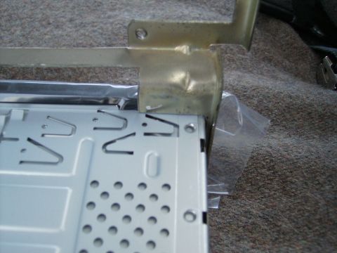 1979 Ford F-100 - The metal chassis and mounting bracket of a car radio are shown, resting on a carpeted surface.