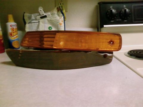 1995 Ford Bronco - Two automotive lenses, one amber and one clear, are displayed on a kitchen counter.
