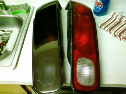 1995 Ford Bronco - A red tail light and a dark tail light are displayed on a counter next to a sink and cleaning supplies.