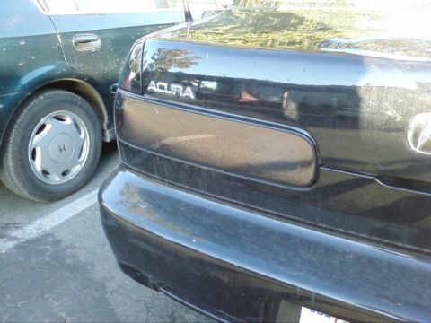 1995 Ford Bronco - Two sedans are parked close together, showing the rear of a black Acura and the side of a dark green car.
