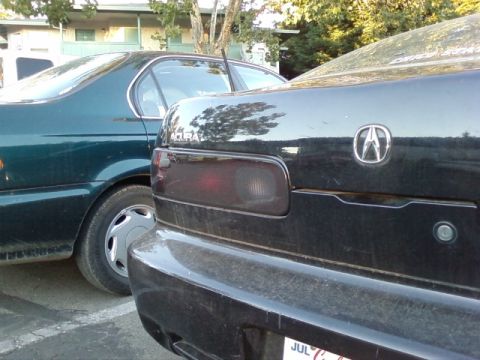 1995 Ford Bronco - Rear view of a black Acura Integra parked next to a dark green sedan.