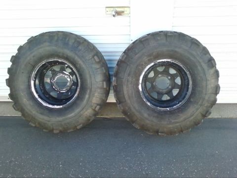 1995 Ford Bronco - A pair of large off-road tires and wheels are displayed in front of a garage door.