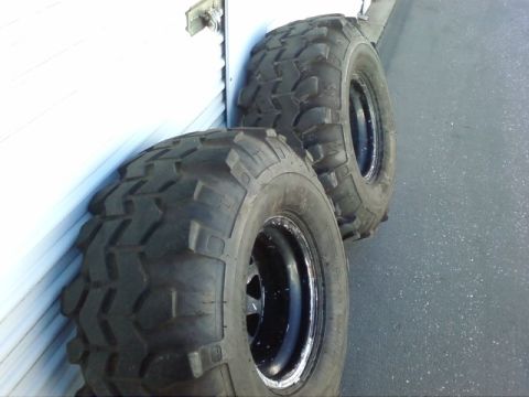 1995 Ford Bronco - These off-road tires and rims are leaning against a white wall.