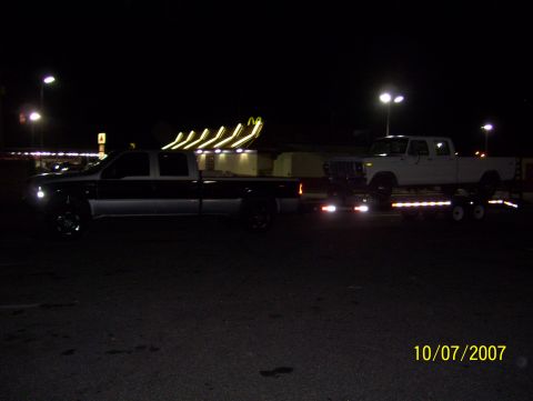 1978 Ford Bronco - A white Ford F-Series truck is loaded onto a trailer at night, with another truck visible in the foreground.