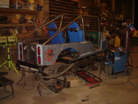1992 Ford Bronco - A custom-built vehicle chassis is in a workshop, undergoing modifications with welding equipment nearby.