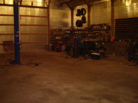 1992 Ford Bronco - A Jeep CJ-5 sits in a cluttered garage, surrounded by tools and automotive parts.