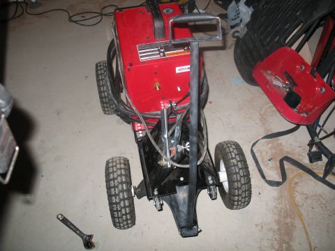 1992 Ford Bronco - A red welding cart with a black frame and wheels is shown in a garage setting.