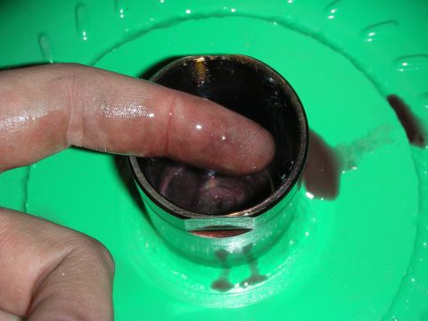 1992 Ford Crown Victoria - Checking fluid level in a metal cylinder with a finger, set against a green background.