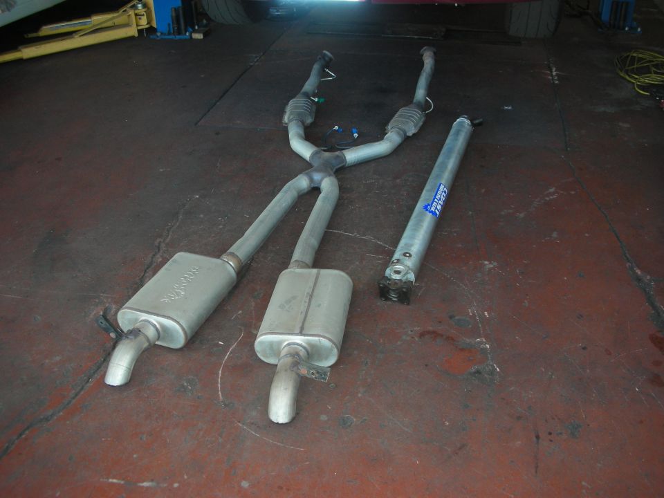 Exhaust mufflers and driveshaft on a garage floor