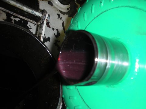 1992 Ford Crown Victoria - Transmission fluid is visible in a metal pipe, with a green component in the background.