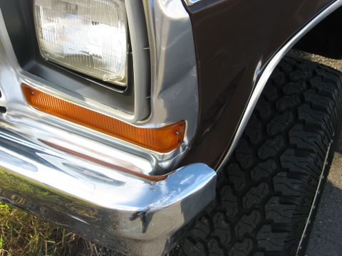 1979 Ford Bronco - Close-up of a brown 1978 Ford Bronco's front corner, showing the headlight, bumper, and tire.