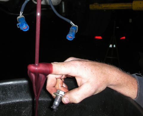 1992 Ford Crown Victoria - Transmission fluid is being drained into a pan, with a finger holding the drain plug.