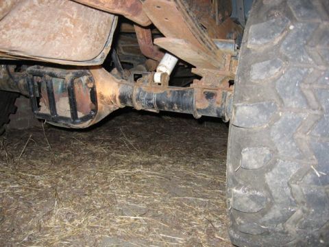 1989 Ford Bronco - Close-up view of the heavily rusted rear axle and suspension system of an older vehicle.