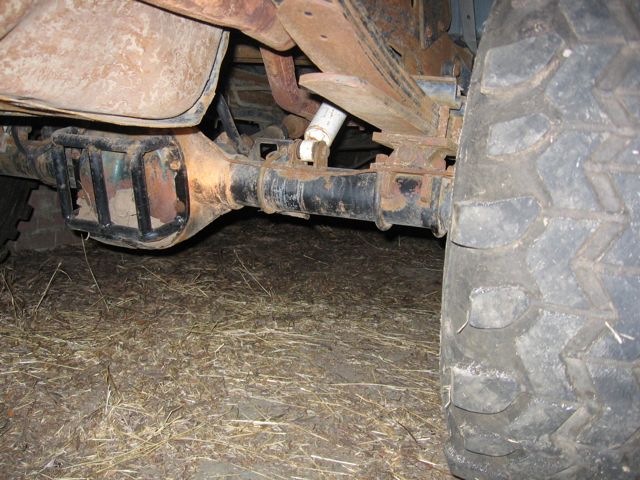 Rusty rear axle assembly with a black protective cage, leaf springs, and a large tire