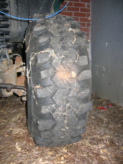 1989 Ford Bronco - A close-up view of a off-road tire, showing its aggressive tread pattern and some debris.