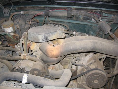 1989 Ford Bronco - The engine bay of a vehicle is shown, covered in dust and grime.