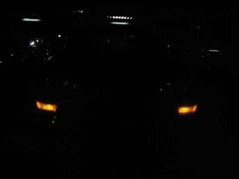 1995 Ford Bronco - The front of a dark SUV is visible at night, with its amber turn signals illuminated.