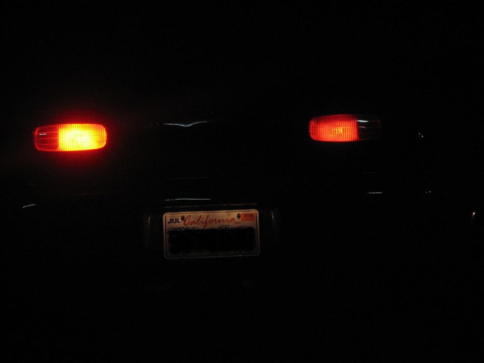 Rear tail lights and California license plate of a dark SUV at night