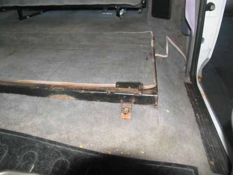 1995 Ford C-350 (Centurion Conversions) - The interior of a vehicle shows a section of carpeted flooring with a metal seat frame and a folded seat base.