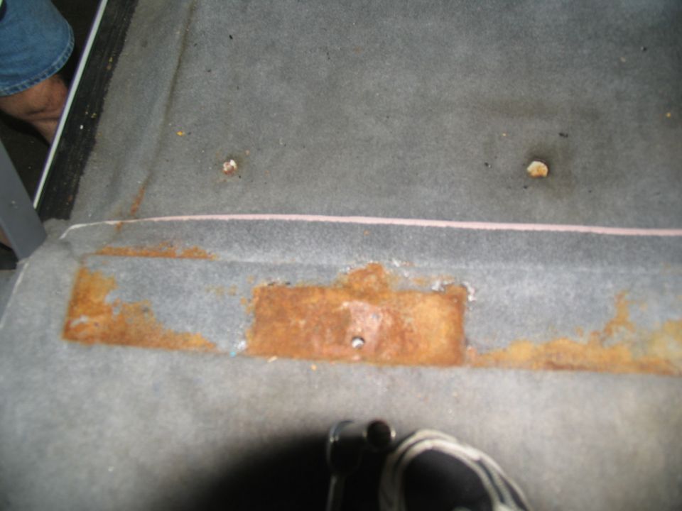 Heavy surface rust around a rectangular mounting plate and bolt studs on a vehicle panel