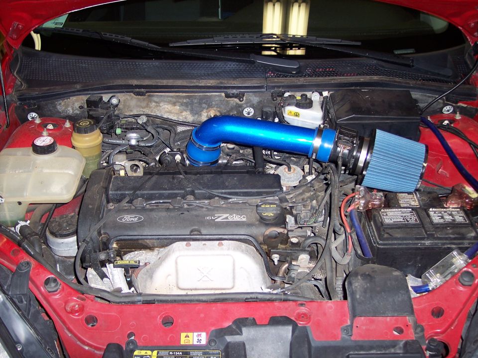 Engine bay of red Ford Focus Zetec with blue aftermarket cold air intake tube and cone filter