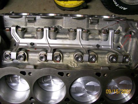 1992 Ford Bronco - Close-up of a bare cylinder head on a bench, showing pedestal-mounted rocker arms and an oil-feed rail, with a hand-drawn red arrow pointin…