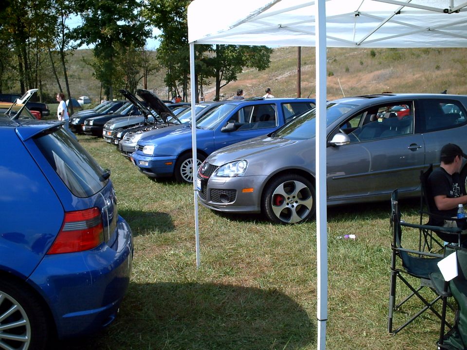 Gray Volkswagen GTI with red brake calipers parked on grass under a white tent